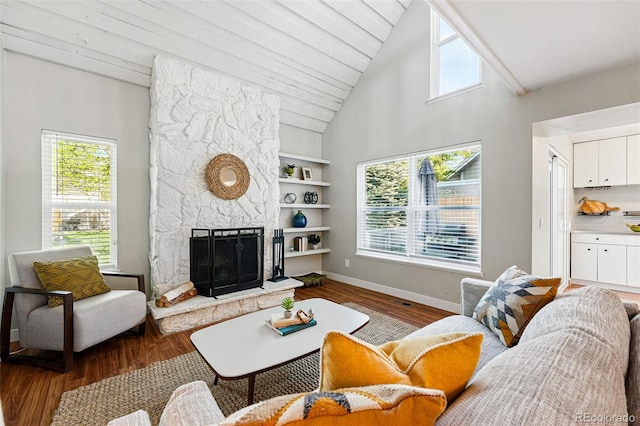 living area featuring wood finished floors, built in features, a fireplace, baseboards, and high vaulted ceiling