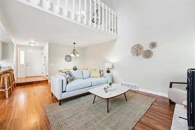 living area with wood finished floors, baseboards, a high ceiling, and a chandelier