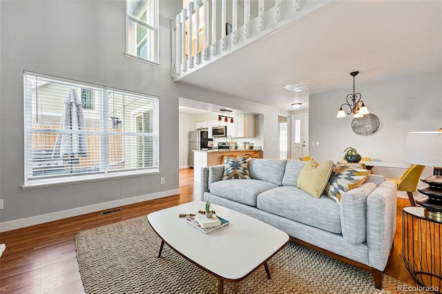 living area with plenty of natural light, wood finished floors, a chandelier, and baseboards