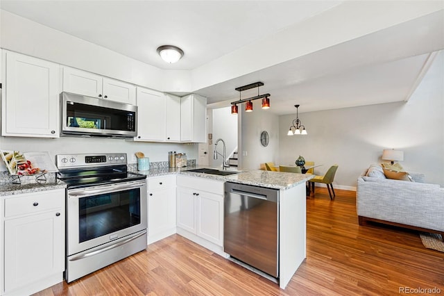 kitchen with stainless steel appliances, a sink, a peninsula, light wood finished floors, and white cabinets