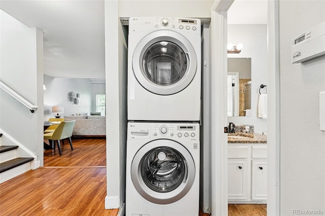 laundry area featuring stacked washer / drying machine and light wood-style floors