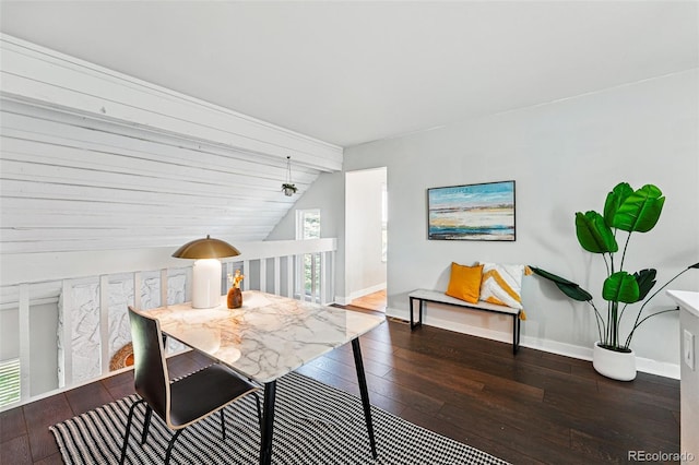 dining room featuring vaulted ceiling, hardwood / wood-style flooring, and baseboards