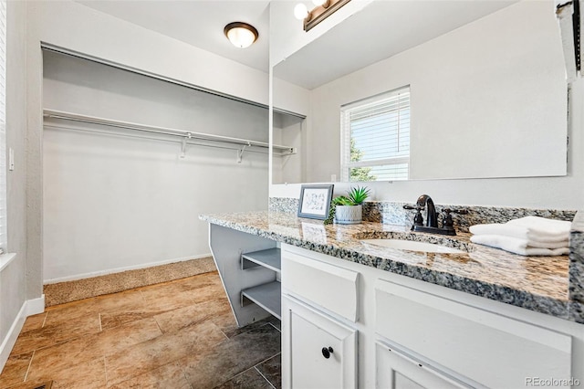 laundry area with a sink, baseboards, and stone finish flooring