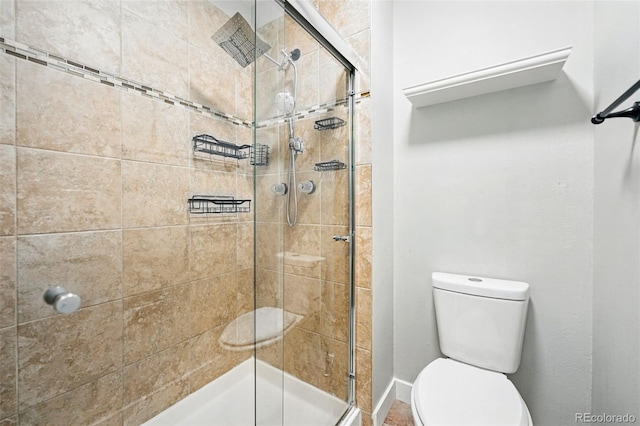 bathroom with a stall shower, toilet, and baseboards