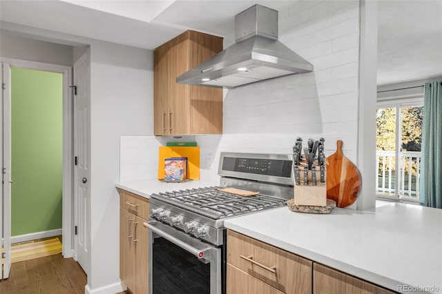 kitchen with tasteful backsplash, dark wood-style floors, extractor fan, light countertops, and stainless steel range with gas cooktop