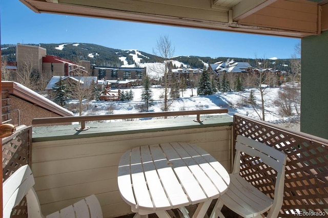 snow covered back of property featuring a mountain view