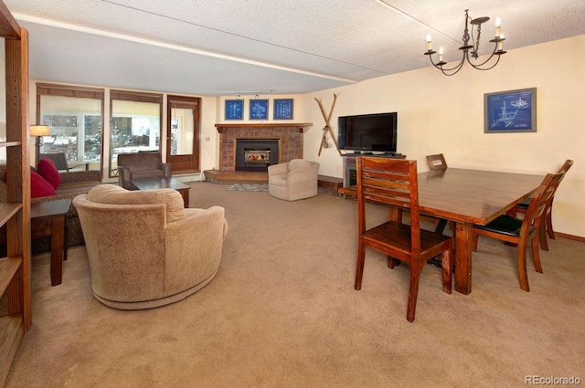 dining room featuring a tiled fireplace, a chandelier, a textured ceiling, and carpet flooring