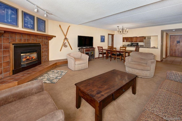 living room with a notable chandelier, a textured ceiling, a tile fireplace, and carpet floors