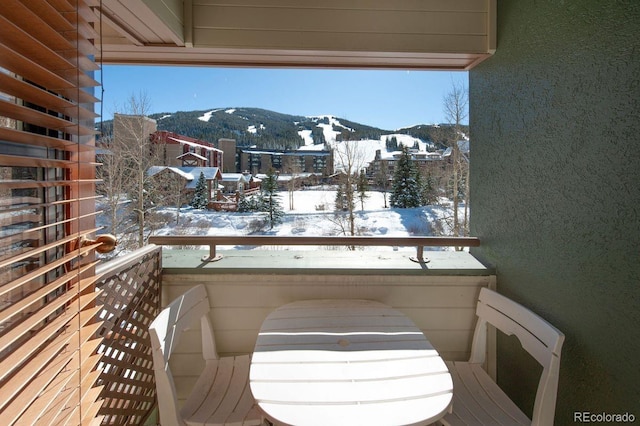 snow covered back of property with a mountain view