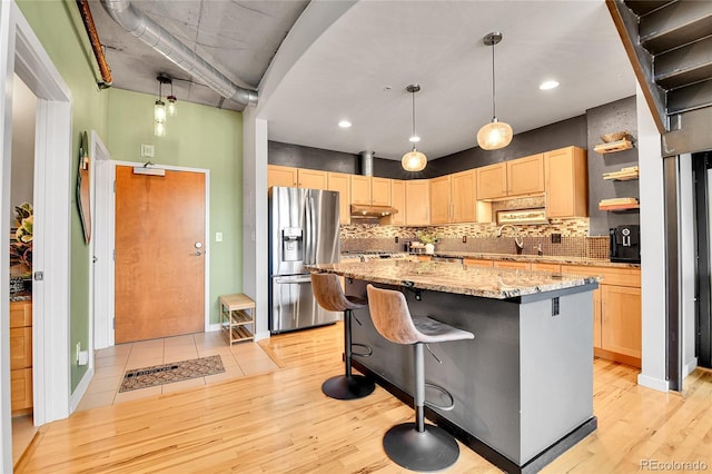 kitchen featuring a kitchen island, a sink, stainless steel fridge with ice dispenser, light brown cabinetry, and light wood finished floors