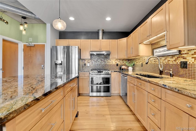 kitchen with stainless steel appliances, light brown cabinetry, a sink, and under cabinet range hood