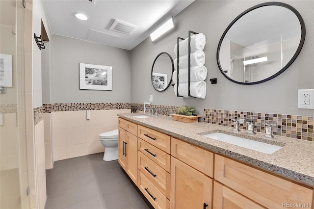 bathroom featuring toilet, visible vents, a sink, and a shower with shower door