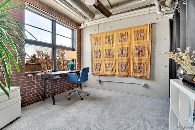 carpeted office featuring brick wall