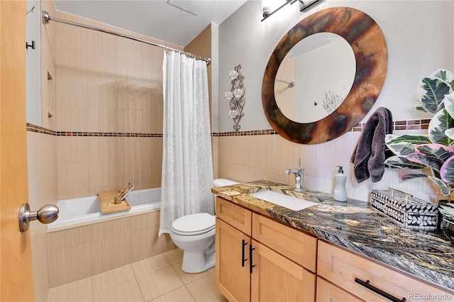 bathroom with toilet, tile patterned flooring, tiled shower / bath, vanity, and tile walls