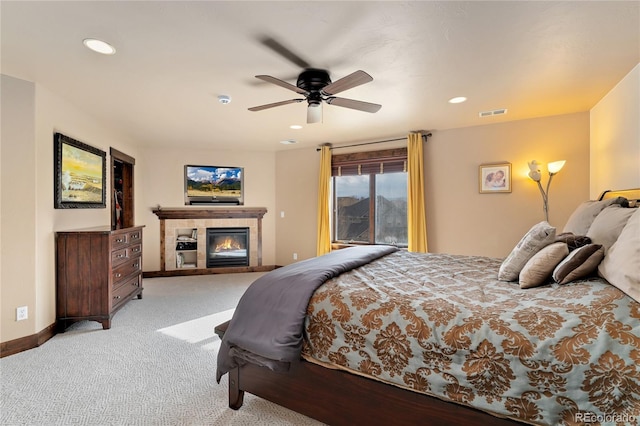 bedroom featuring carpet, a tiled fireplace, recessed lighting, a ceiling fan, and baseboards