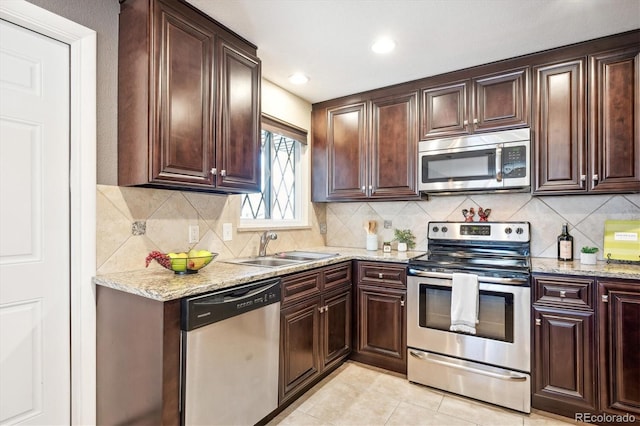 kitchen featuring tasteful backsplash, light tile patterned flooring, stainless steel appliances, light stone countertops, and sink