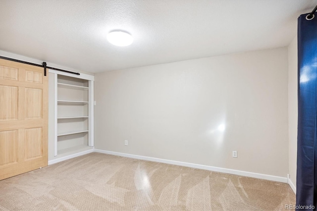 unfurnished bedroom featuring a closet, a barn door, carpet flooring, and a textured ceiling