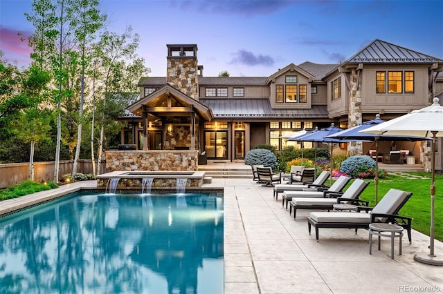 back of property at dusk featuring metal roof, fence, a fenced in pool, a standing seam roof, and a patio area