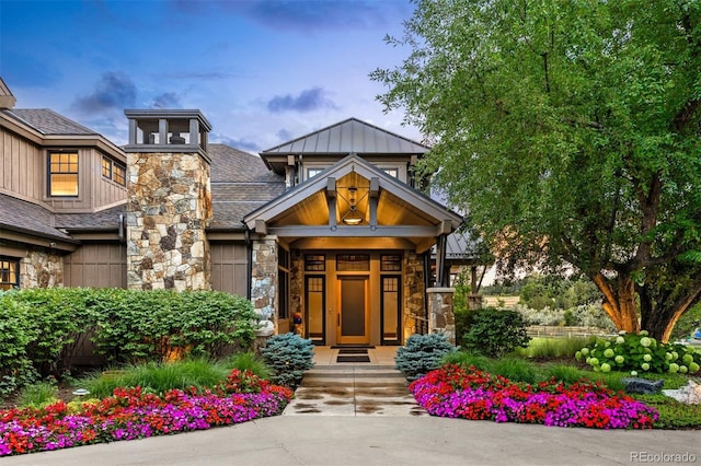 view of exterior entry featuring stone siding and roof with shingles