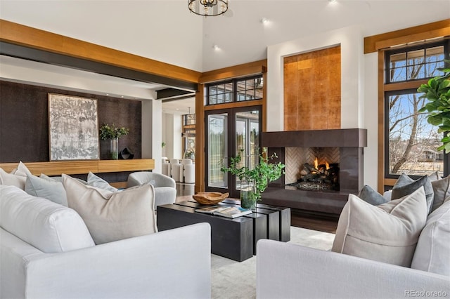 living area with a lit fireplace, french doors, and a towering ceiling