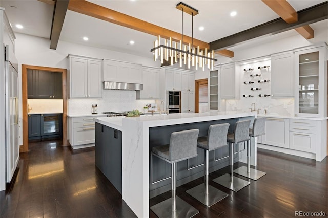 kitchen featuring dark wood-style floors, tasteful backsplash, a breakfast bar area, and beam ceiling