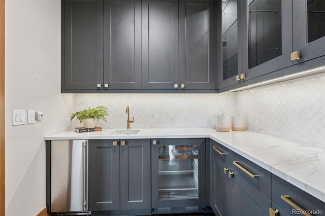 bar featuring freestanding refrigerator, beverage cooler, a sink, and backsplash