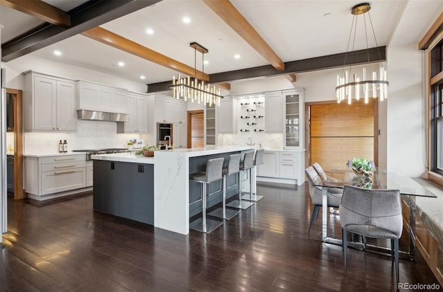 kitchen featuring exhaust hood, light countertops, backsplash, and a kitchen breakfast bar