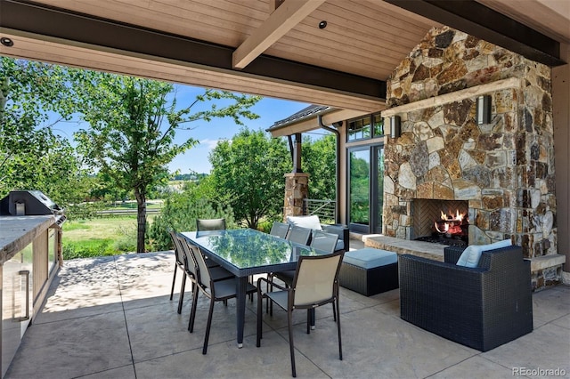 view of patio / terrace with outdoor dining area, an outdoor stone fireplace, and area for grilling