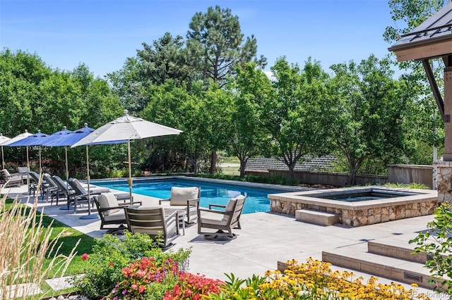 outdoor pool featuring a patio, fence, and an in ground hot tub