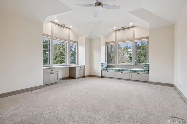 additional living space featuring light colored carpet, vaulted ceiling, built in desk, and baseboards