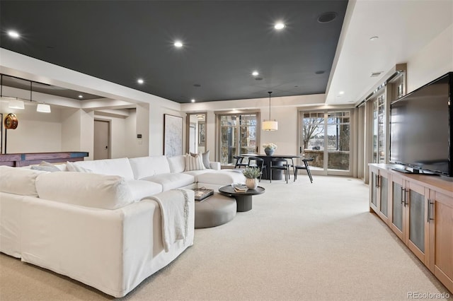 living room with light carpet, a tray ceiling, and recessed lighting