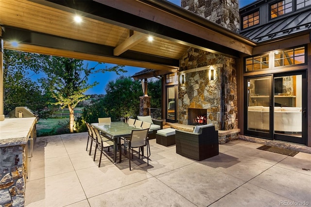 view of patio / terrace with outdoor dining space and an outdoor stone fireplace