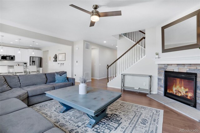 living room featuring wood-type flooring, a fireplace, and ceiling fan