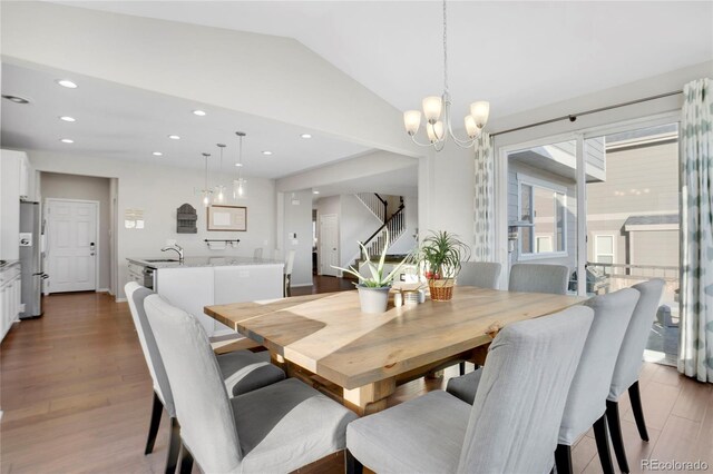 dining room with sink, vaulted ceiling, a chandelier, and light hardwood / wood-style flooring