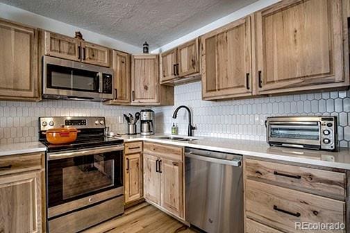 1143 Straight Creek Dr Unit H103, Dillon, CO 80435 - kitchen featuring stainless steel appliances, a toaster, a textured ceiling, a sink, and light countertops