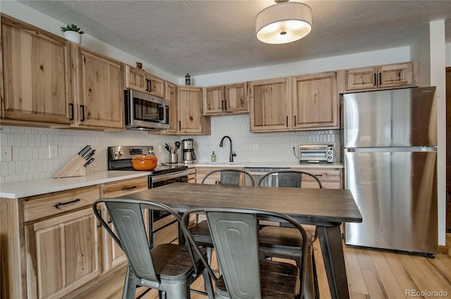 1143 Straight Creek Dr Unit H103, Dillon, CO 80435 - kitchen with stainless steel appliances, backsplash, light brown cabinets, a sink, and light wood-style flooring