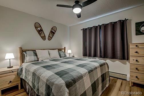 1143 Straight Creek Dr Unit H103, Dillon, CO 80435 - bedroom featuring a baseboard heating unit, wood finished floors, and ceiling fan