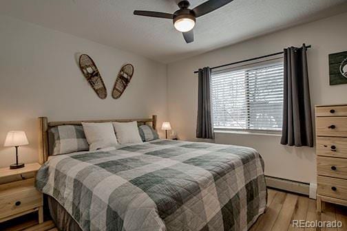 1143 Straight Creek Dr Unit H103, Dillon, CO 80435 - bedroom with a ceiling fan, light wood-style floors, and a baseboard radiator
