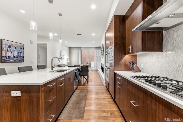 kitchen featuring pendant lighting, sink, a spacious island, a kitchen bar, and wall chimney exhaust hood