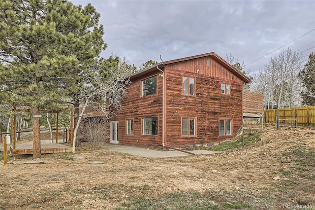 view of side of property featuring fence, a wooden deck, and a patio area