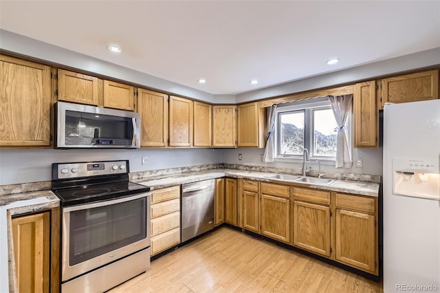 kitchen featuring a sink, stainless steel appliances, light wood-type flooring, recessed lighting, and light countertops