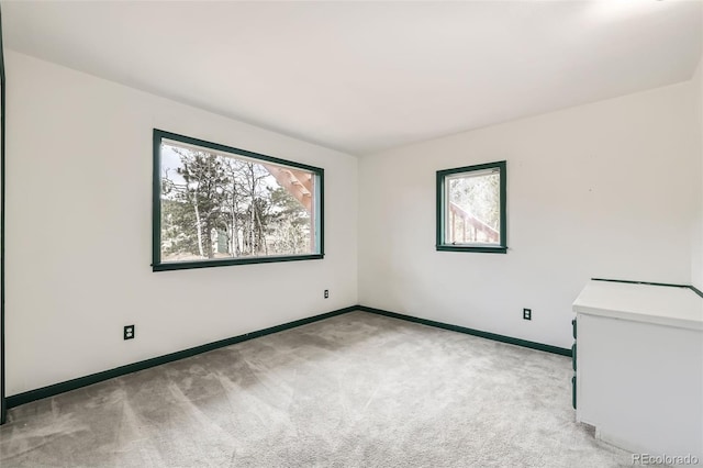 unfurnished room featuring baseboards and light carpet