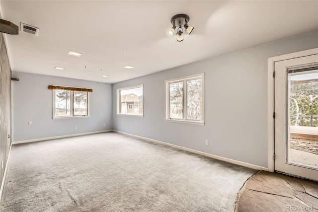 spare room with carpet flooring, baseboards, and visible vents