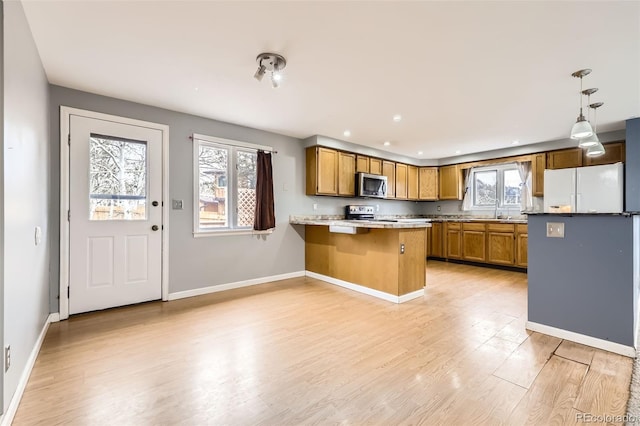 kitchen with a wealth of natural light, a peninsula, appliances with stainless steel finishes, and a sink