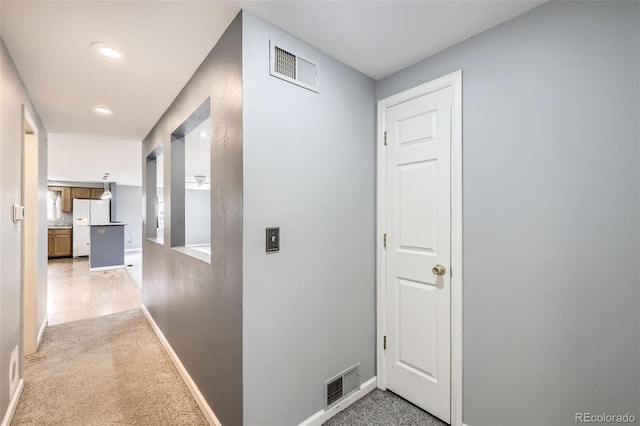 corridor featuring baseboards, recessed lighting, visible vents, and light colored carpet