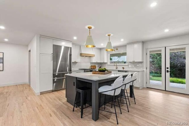 4 Doral Ln, Littleton, CO 80123 - kitchen featuring high end refrigerator, premium range hood, recessed lighting, white cabinetry, and light wood-type flooring