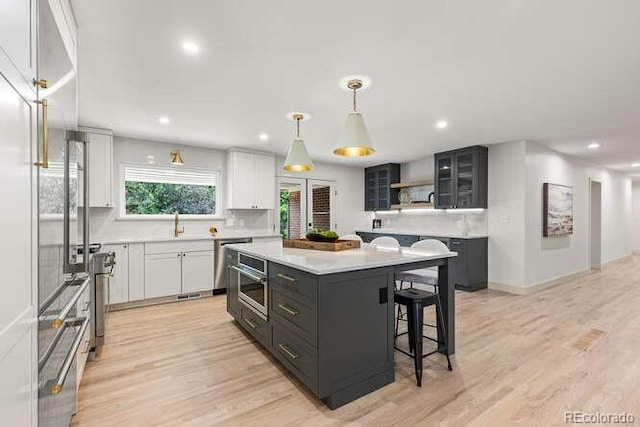 4 Doral Ln, Littleton, CO 80123 - kitchen with a kitchen island, a kitchen breakfast bar, light countertops, light wood-style floors, and recessed lighting