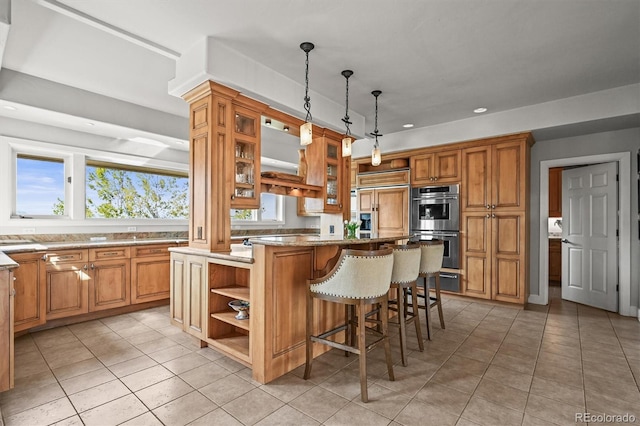 1425 Autumnwood Ln, Evergreen, CO 80439 - kitchen with open shelves, double oven, a breakfast bar, light tile patterned flooring, and paneled refrigerator