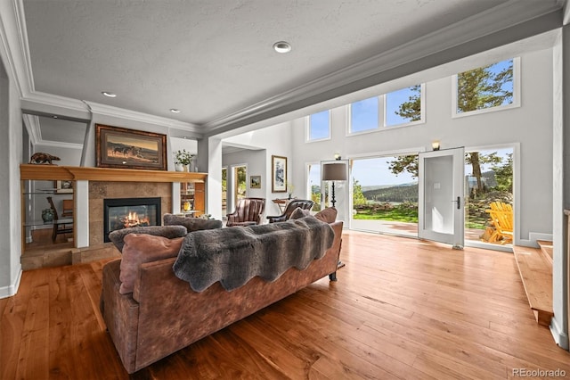 1425 Autumnwood Ln, Evergreen, CO 80439 - living area with crown molding, a tiled fireplace, hardwood / wood-style floors, and recessed lighting