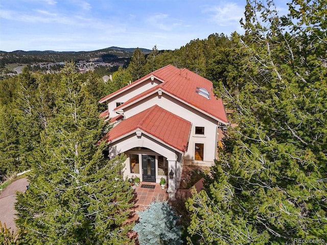 1425 Autumnwood Ln, Evergreen, CO 80439 - view of front facade featuring french doors, stucco siding, metal roof, a mountain view, and a view of trees